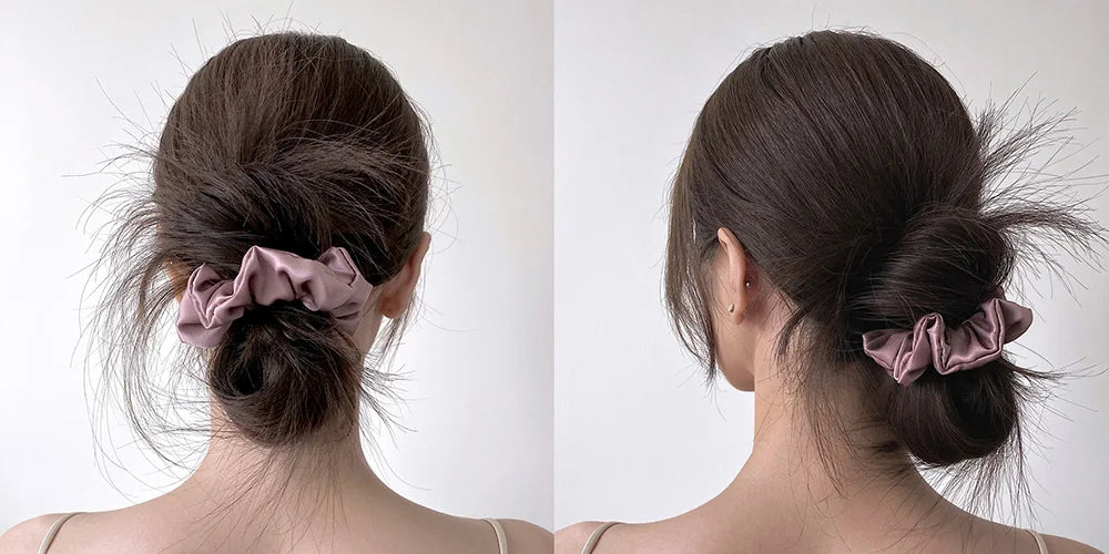 A close-up of a woman's hair styled in a low bun with pink silk scrunchies.