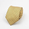 A yellow necktie with a blue dot pattern folded and displayed against a white background.