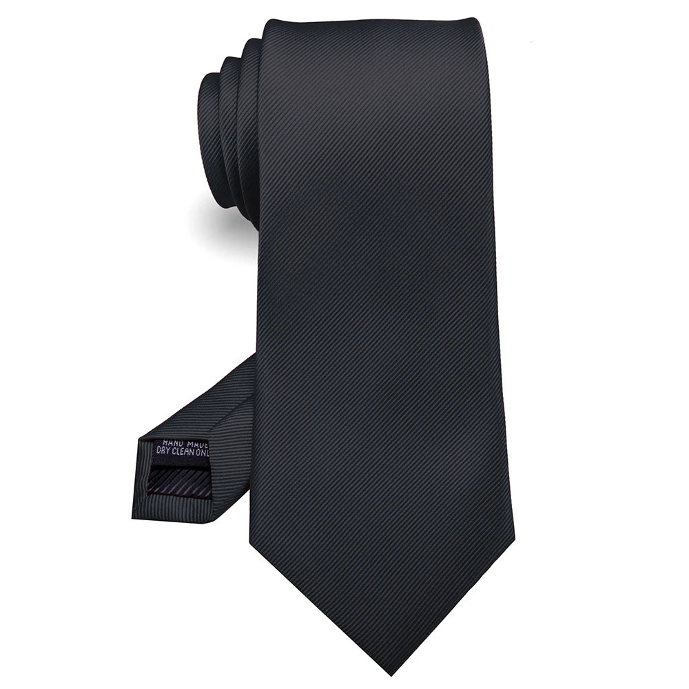 Cravate en soie jacquard noire roulée et présentée sur fond blanc.