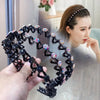 A hand holds a black elastic hair hoop adorned with sparkling pink and clear rhinestones.