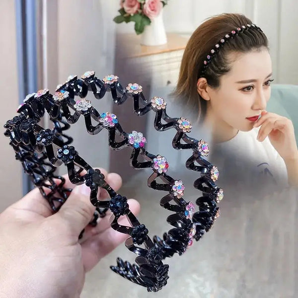 Una mano sostiene un aro de pelo elástico negro adornado con pedrería rosa y transparente brillante.
