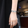 A close-up of a woman's wrist wearing a silver scripture quote bracelet on her hand.