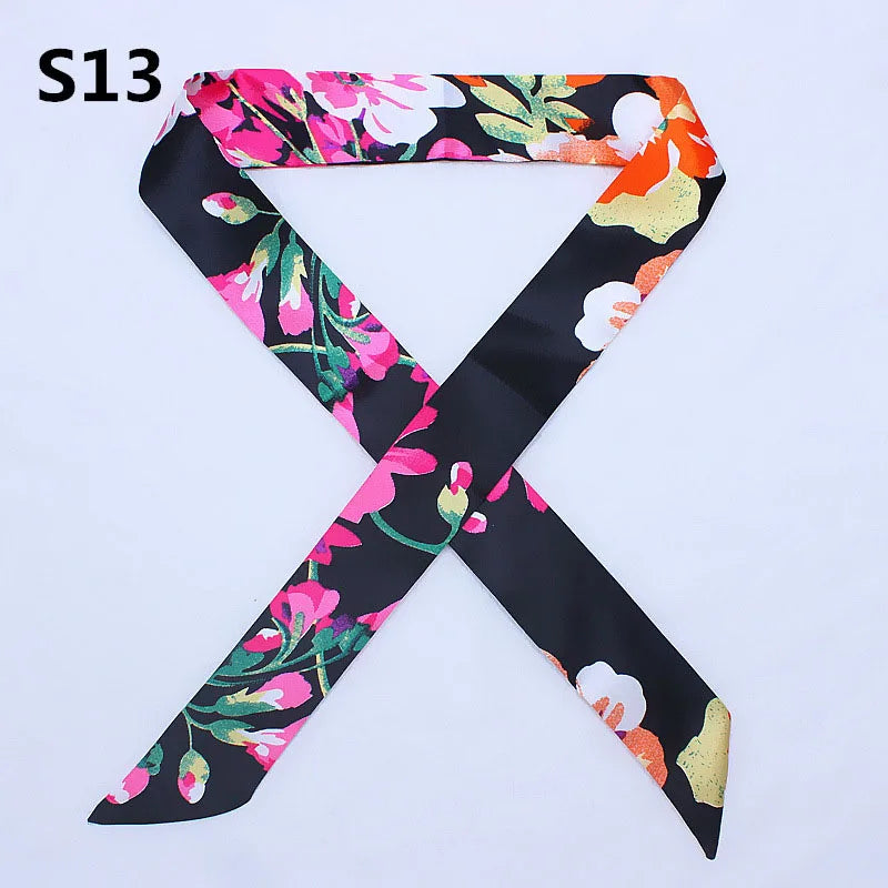 A black silk headband scarf featuring a multi-color floral print with pink, orange, and white flowers.