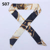 A black and cream silk scarf or headband featuring an ornate gold chain pattern.