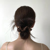 A woman's dark hair is styled in a messy bun with silk scrunchies.