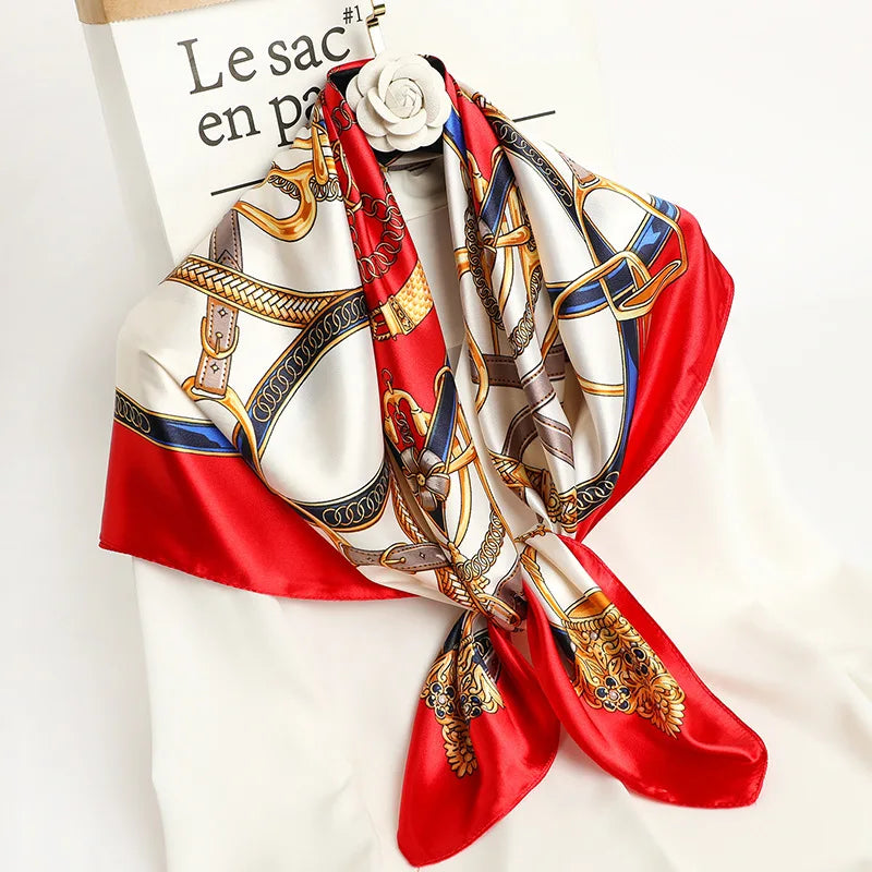A luxury satin silk scarf featuring intricate gold and blue patterns on a red background