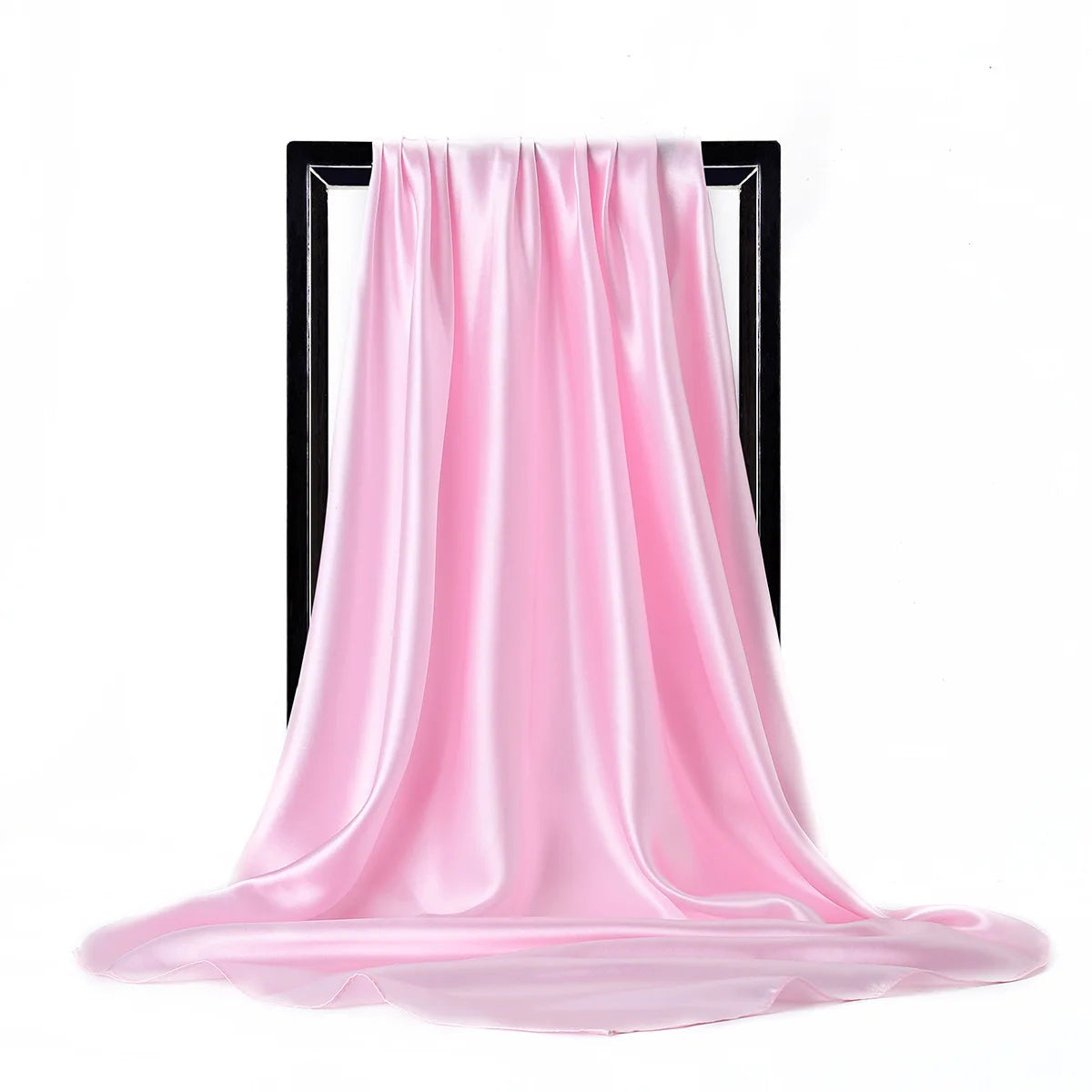 Una bufanda de seda satinada rosa fluida drapeada sobre un soporte negro.