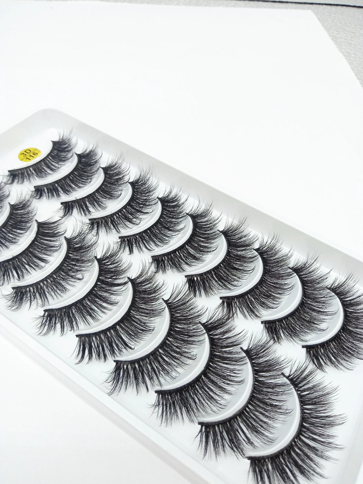 A display of dramatic mink false eyelashes arranged in a fan pattern on a white tray.