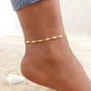 A close-up of a woman's ankle wearing a delicate gold stainless steel anklet.