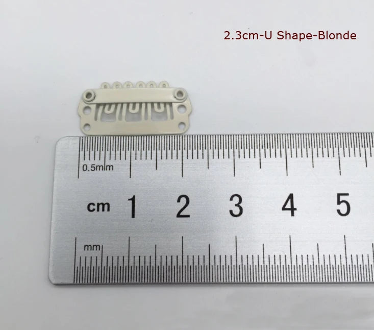 Une pince pour extensions de cheveux blonde avec une règle pour l'échelle.