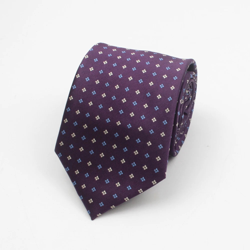 A purple necktie with a small blue dot pattern rolled up.