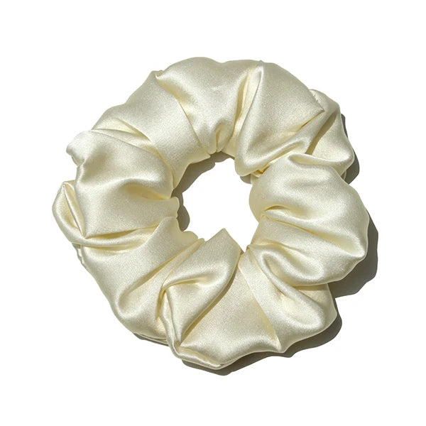 A beige luxury pure silk hair scrunchie tied in a voluminous, gathered bow.