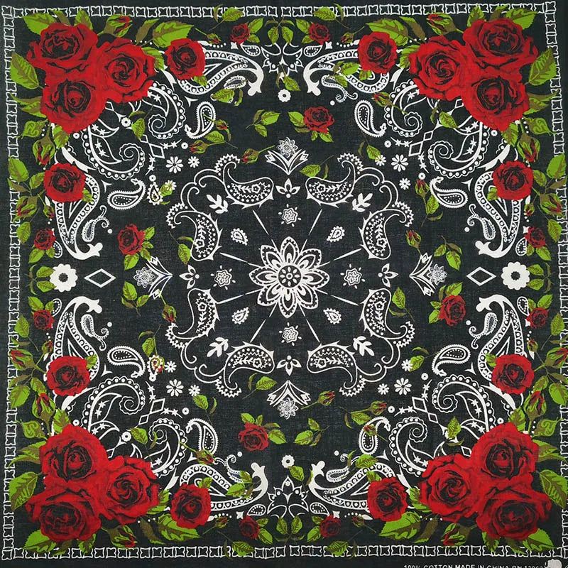 Estampado de tela oscura con rosas rojas y patrones de pergamino blanco sobre fondo negro.