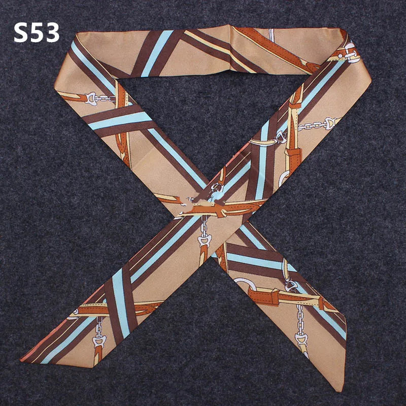 A beige and brown striped silk headband scarf with metal accents laid out on a dark gray fabric.