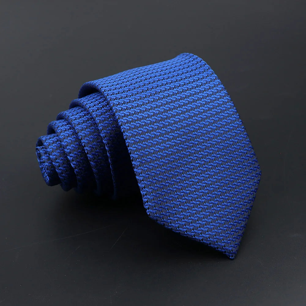 A dark blue classic men's tie with a textured pattern is shown folded on a dark surface.