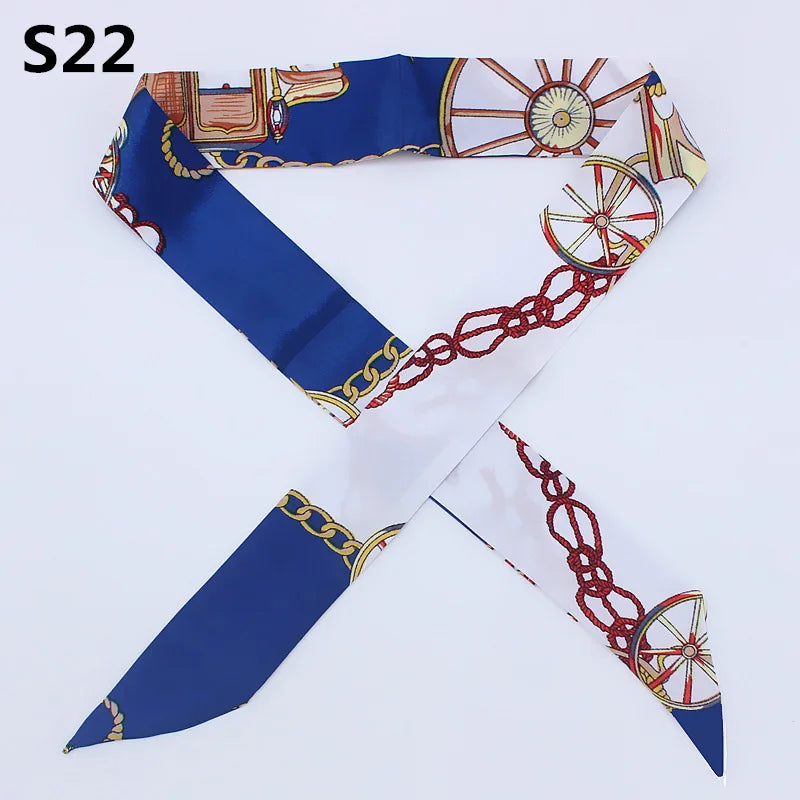 A blue silk headband scarf featuring a multi-color leopard print design with gold chain and wheel accents.