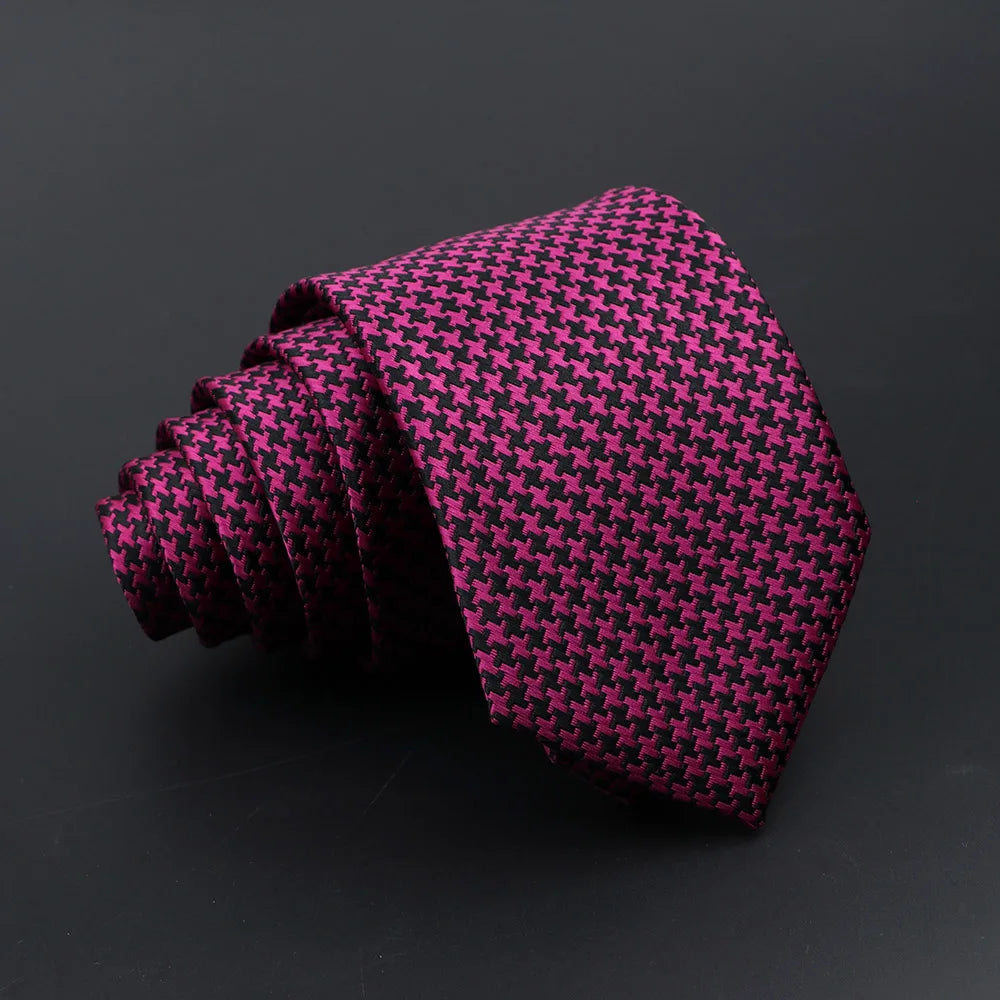 A dark magenta plaid tie is rolled and displayed against a black background.