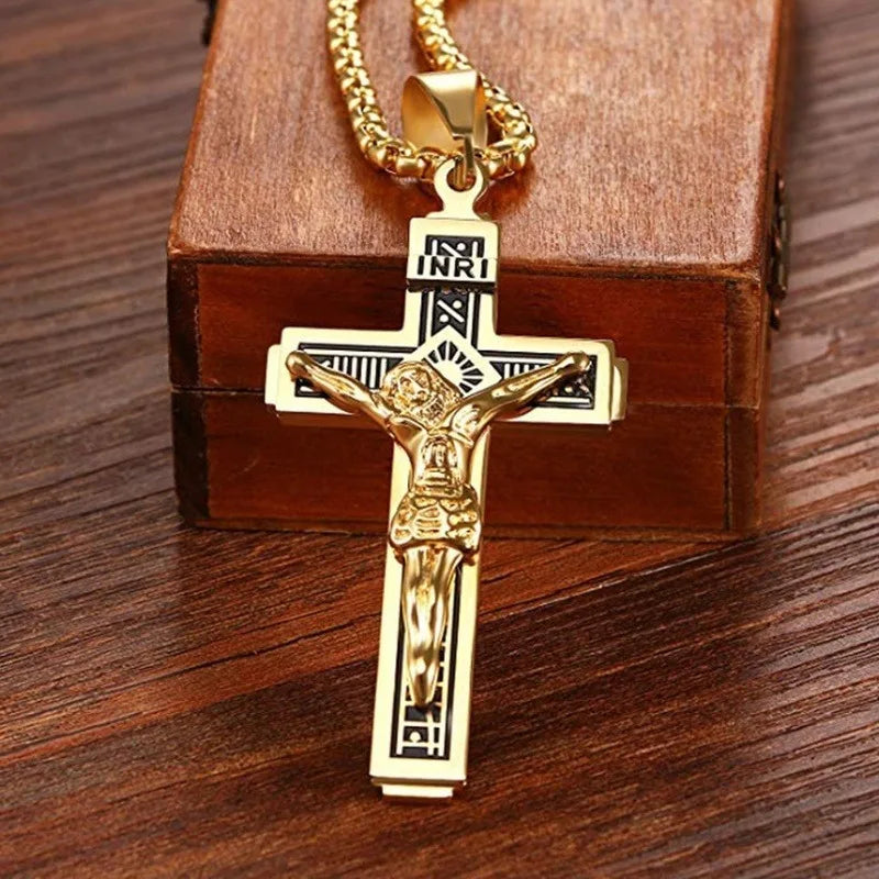 A gold-colored retro Christian cross amulet necklace displayed on a brown wooden box.