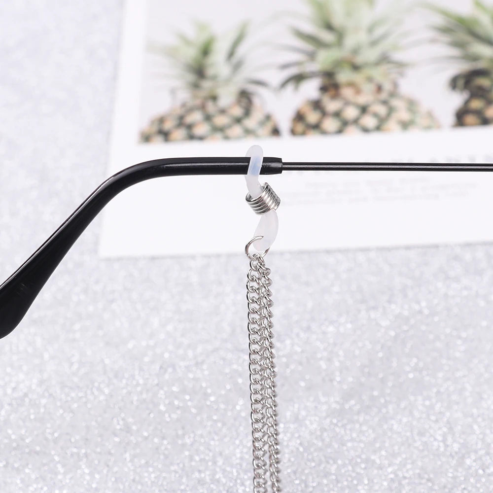 A silver chain with a pearl charm is attached to a black eyeglass lanyard hook.