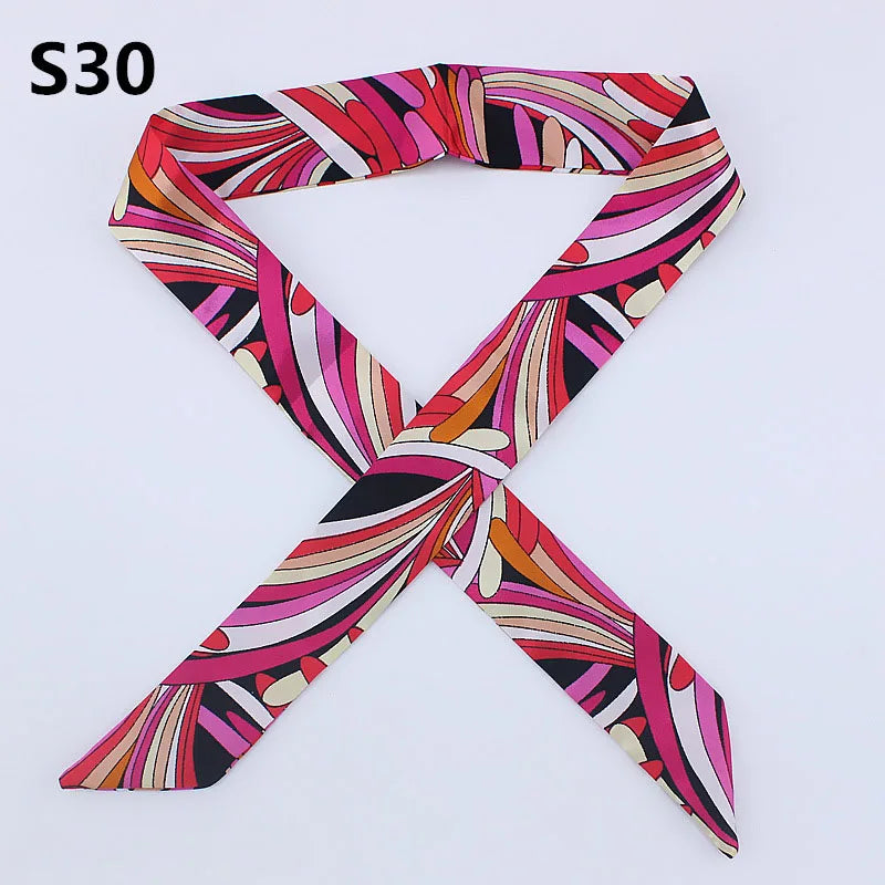 A patterned silk headband scarf featuring multi-color abstract stripes in pink, red, black, and orange.