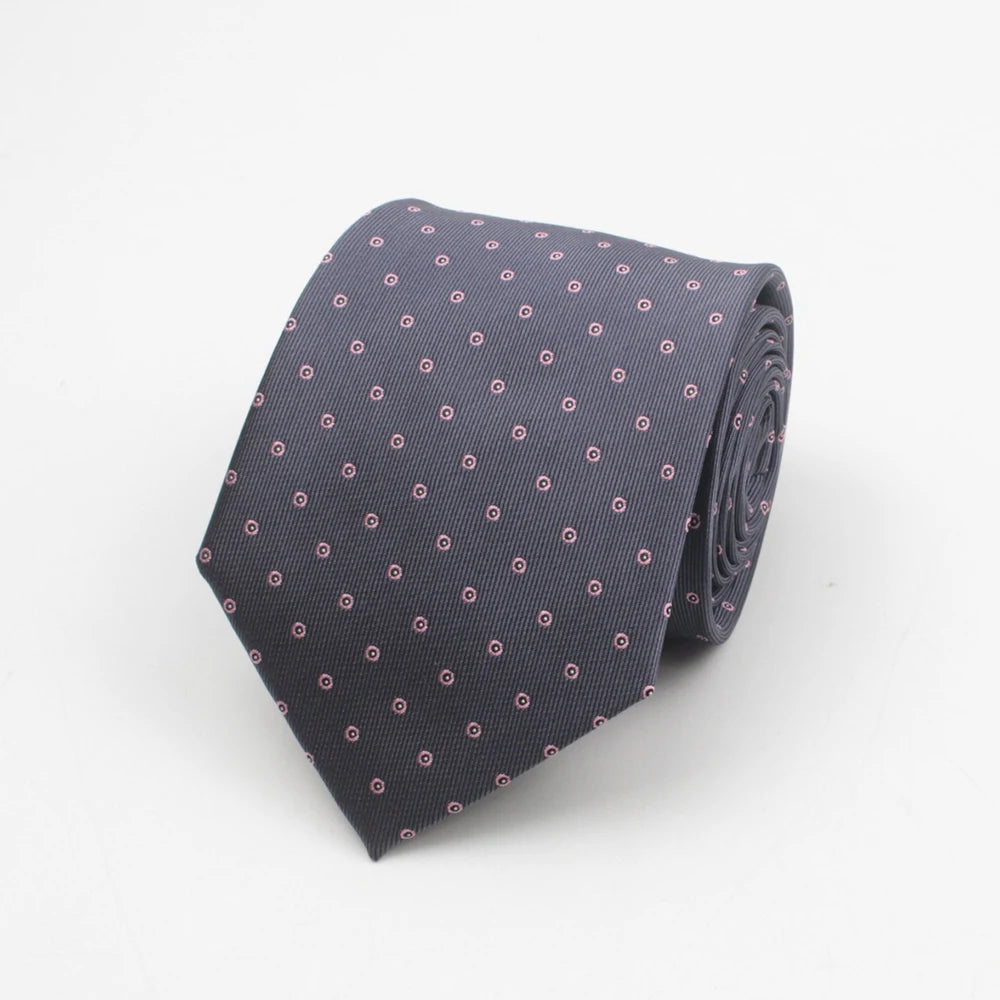 A dark gray necktie with a small repeating pink dot pattern folded neatly.
