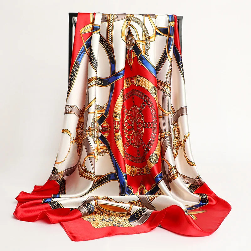 A luxurious satin silk scarf featuring intricate gold and blue patterns on a red background.