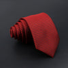 A red classic men's tie with a textured plaid pattern, rolled and displayed on a dark surface.
