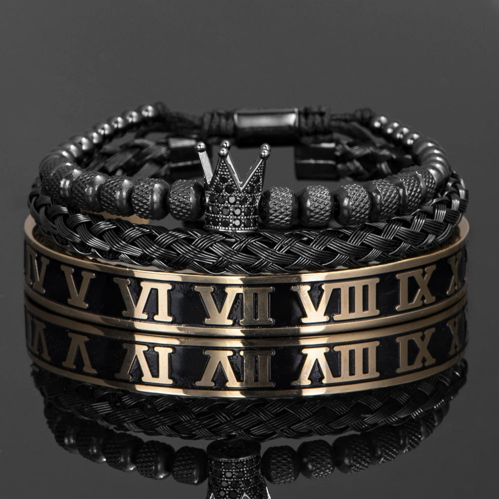 Pila de pulseras de esmalte negro y dorado con diseño de corona sobre una superficie reflectante.