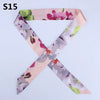 Pink silk headband scarf with multi-color floral print in shades of purple, green, and mauve.