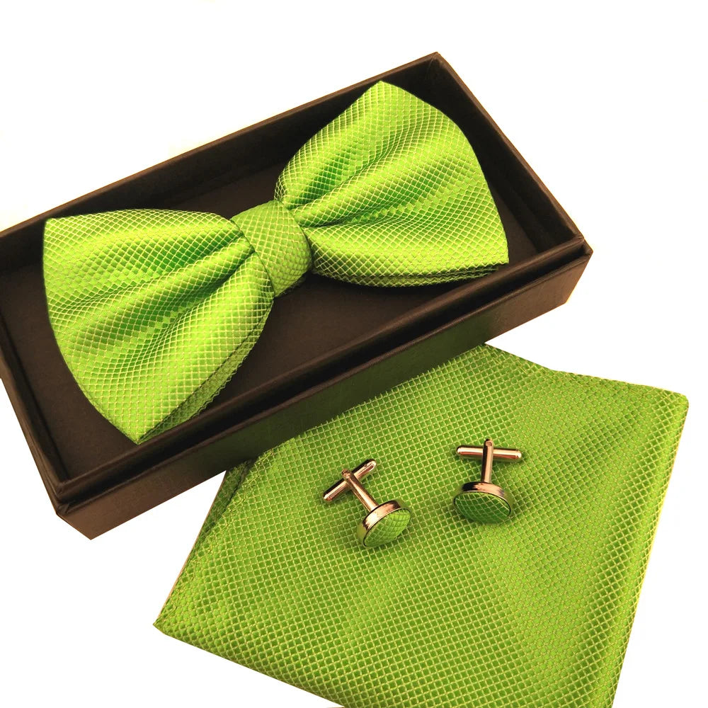 A lime green bow tie and cufflinks set displayed in a brown box and on a matching fabric.