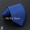 A dark blue patterned tie is rolled and displayed on a black background.