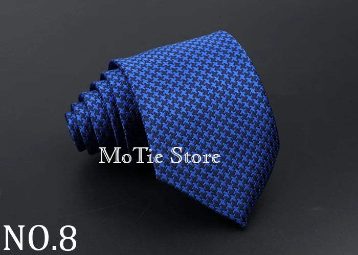 A dark blue patterned tie is rolled and displayed on a black background.