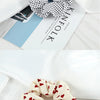 A close-up of a knitted fabric scrunchie headband in cream and red floral pattern resting on white fabric.