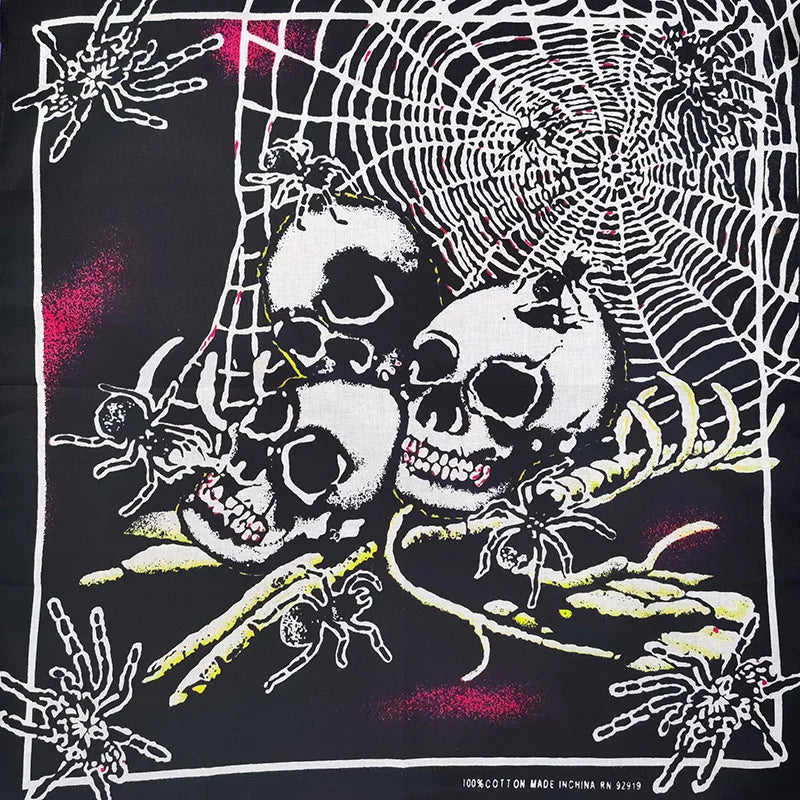 Diseño gráfico en blanco y negro con calaveras, arañas y una telaraña sobre fondo de tela.