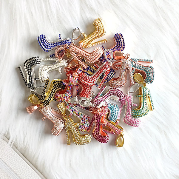A collection of elegant high heel shoe charms in various colors and finishes displayed on a white background.