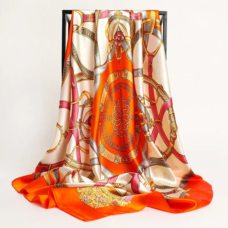 A luxurious satin silk scarf featuring an intricate orange and gold pattern with pink accents.