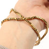 Gold-plated hematite round cube beads strung together on a wrist.