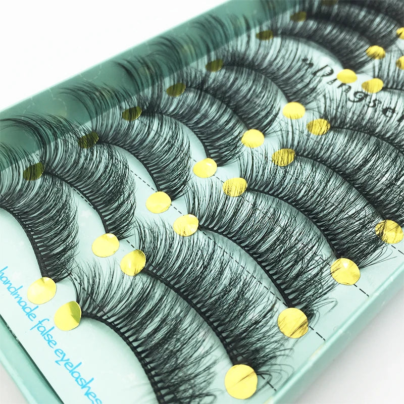 A tray of black mink false eyelashes is displayed on a light green surface.