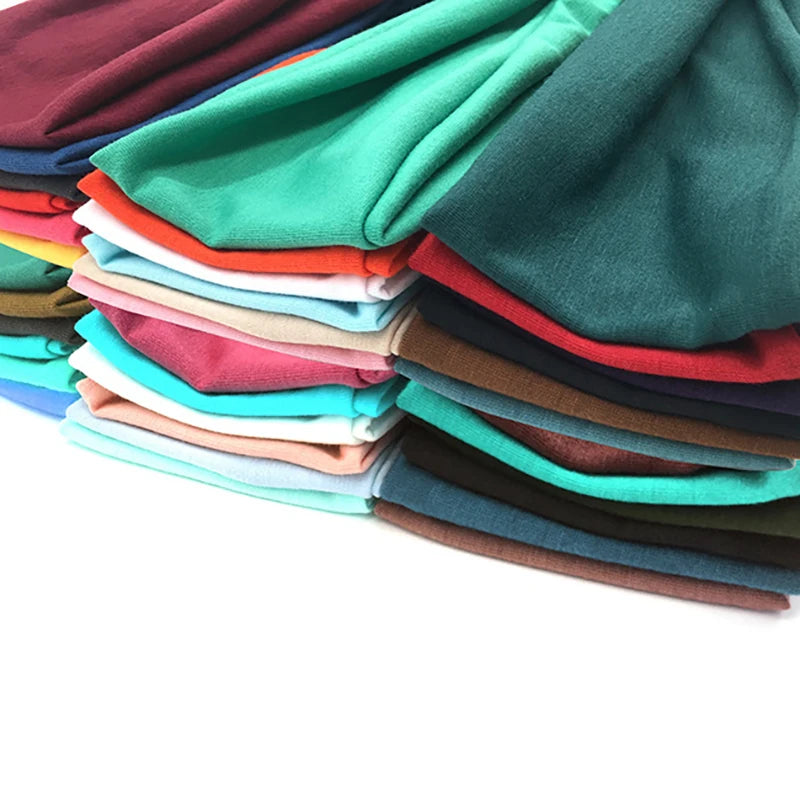 Ein Stapel von Baumwoll-Twisted-Headbands in verschiedenen Grüntönen, Türkis-, Rot- und Brauntönen.
