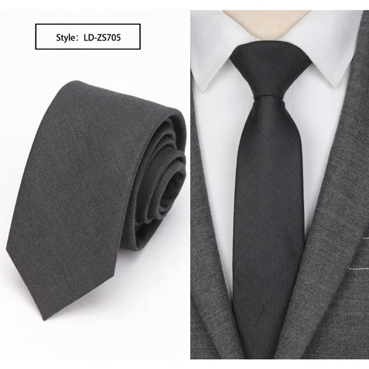 A dark gray slim fit wool neck tie shown folded and worn under a gray suit jacket.