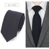 A dark charcoal slim fit wool neck tie worn with a gray suit jacket and white shirt.