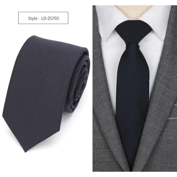 A dark charcoal slim fit wool neck tie worn with a gray suit jacket and white shirt.
