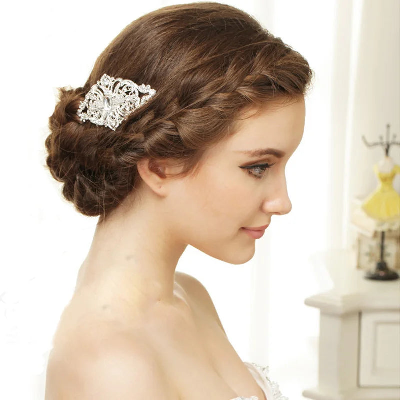 A close-up of a woman's hair styled in an elegant updo adorned with a silver rhinestone bridal hair comb tiara.