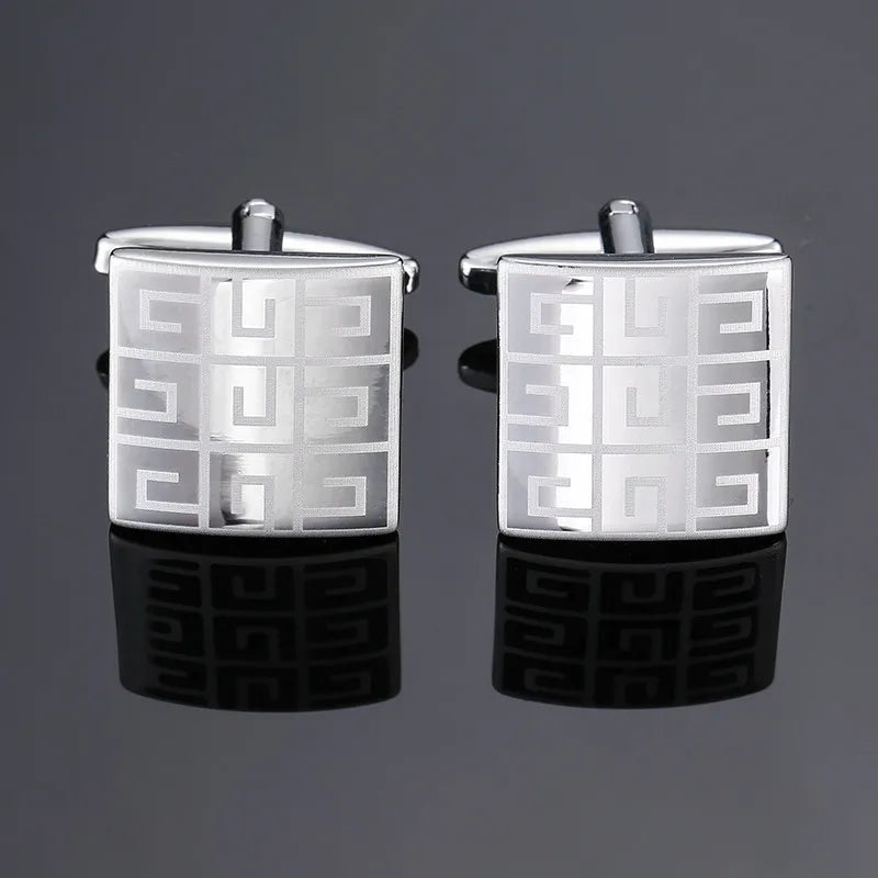 A pair of silver cufflinks featuring a geometric square design with a Greek key pattern.