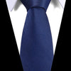 A close-up of a dark blue silk jacquard tie tied in a formal knot against a white shirt collar.