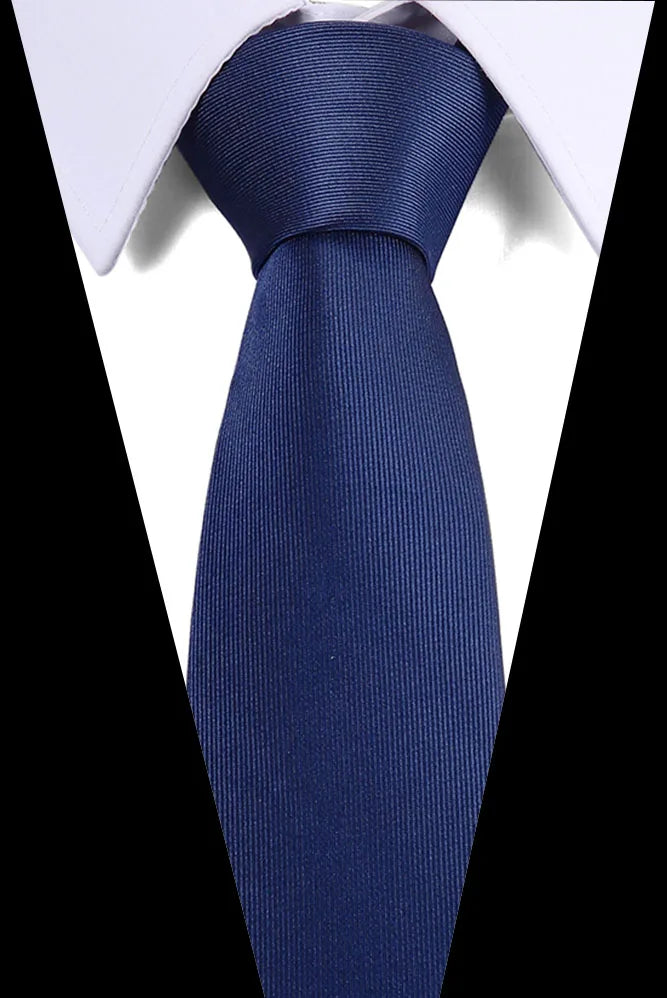 A close-up of a dark blue silk jacquard tie tied in a formal knot against a white shirt collar.