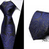 A dark blue silk jacquard tie with an ornate pattern shown in a vertical and folded view.