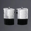 A pair of silver square cufflink holders with a geometric pattern displayed on a dark reflective surface.