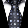 Black silk jacquard tie with small blue floral pattern shown against a white shirt.