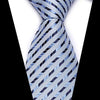 A close-up of a blue and silver silk jacquard tie tied in a knot against a white shirt.